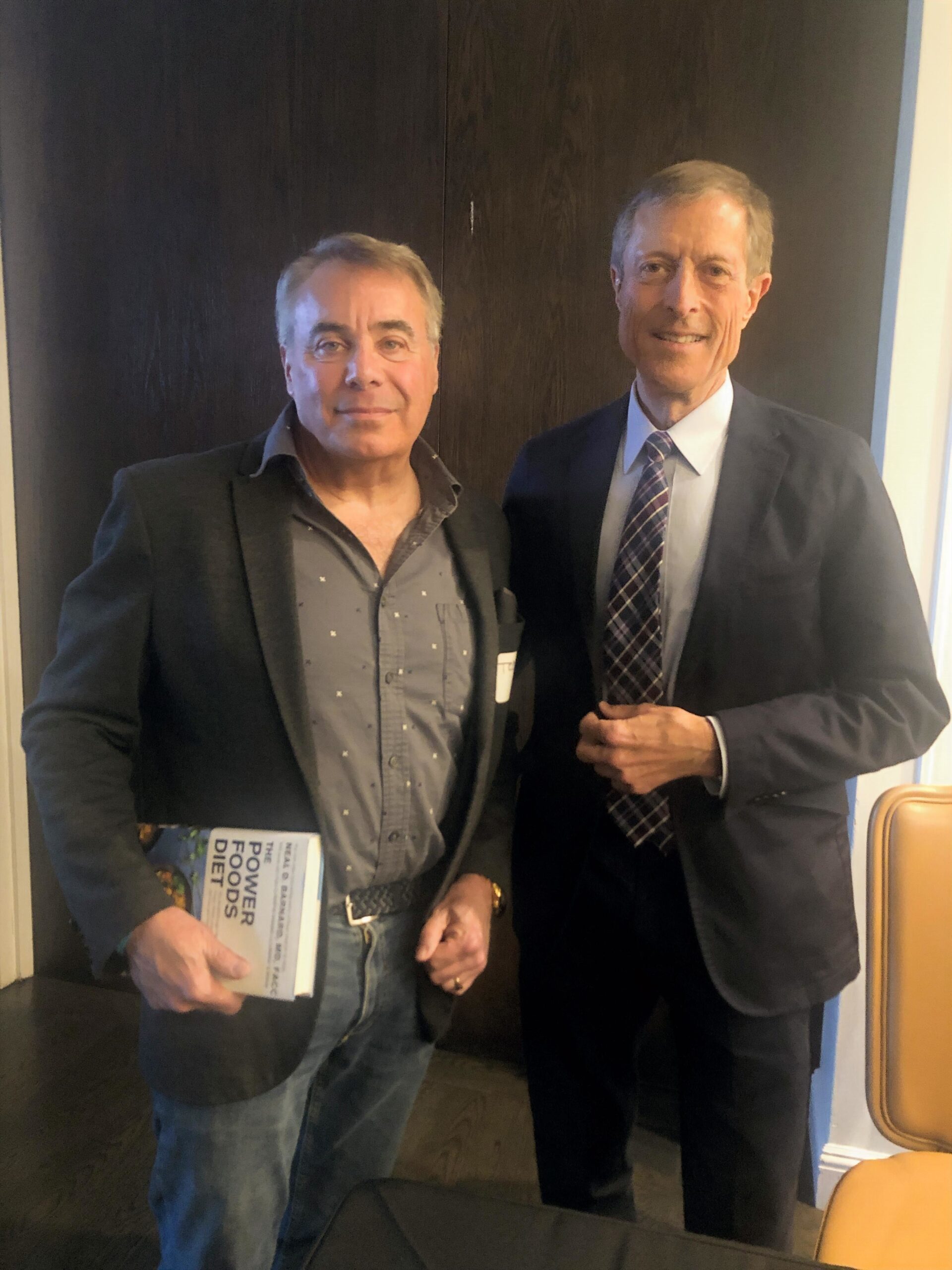 2 men standing, one on the left carrying a book